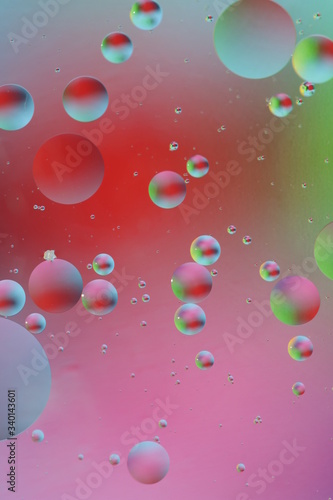 macro of oil mixed with water on colorful red, pink, green, blue background, colourful circles, copy space, vertical © Lyudmila