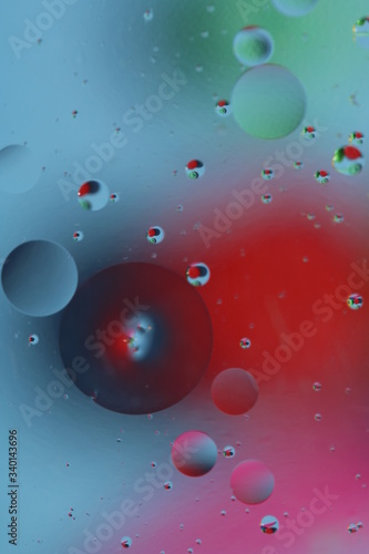 macro of oil mixed with water on colorful red, pink, green, blue background, colourful circles, copy space, vertical