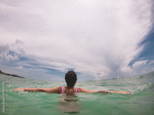 Young girl with bikini swimming at the green and calypso ocean with cloudy sky  Riviera Maya  Mexico