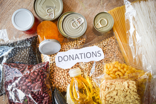 Donations food with canned food on wooden table background / pasta canned goods and dry food non perishable with pea beans cooking oil instant noodles macaroni donate concept