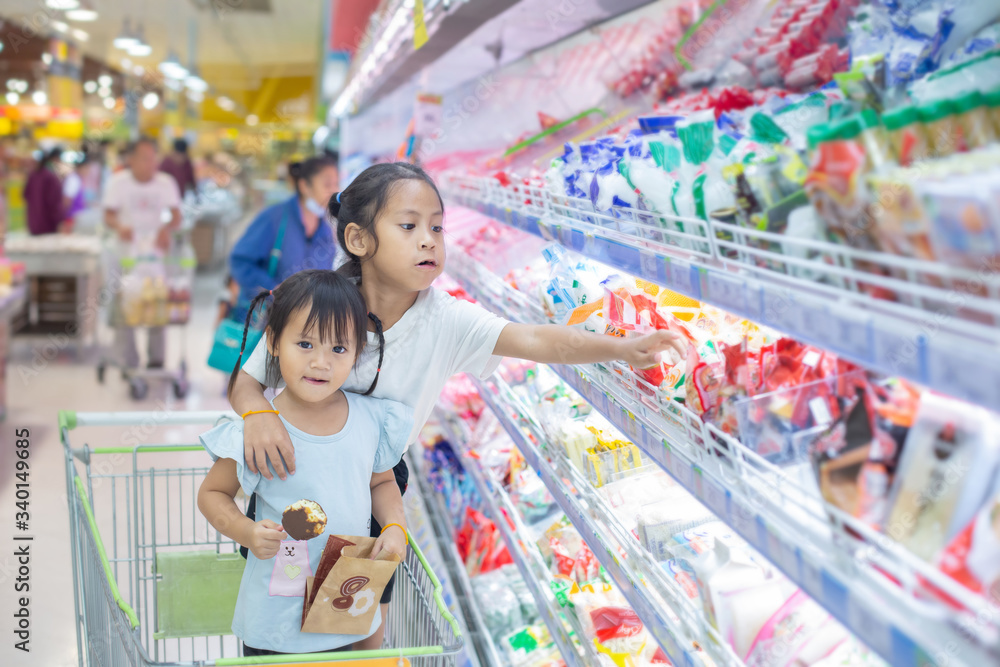 Asian children girl  on the cart shopping choose to see fresh food in department store.
