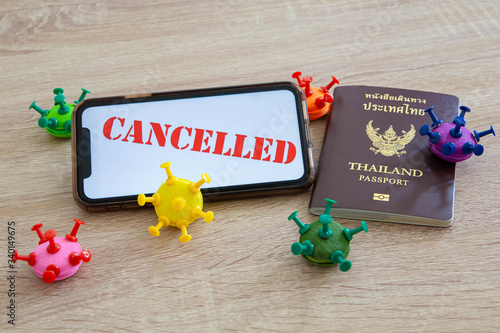 Trip cancelled, concept of self quarantine to prevent spreading of coronavirus infection. Thai passport, coronavirus model made from modelling clay and pin on wooden table, selective focus
