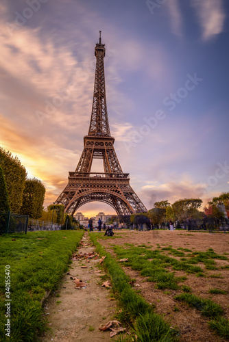 Fototapeta Naklejka Na Ścianę i Meble -  Paris, France 2017 Public park with grassy lawns and walking paths located at the foot of the Eiffel Tower during sunset