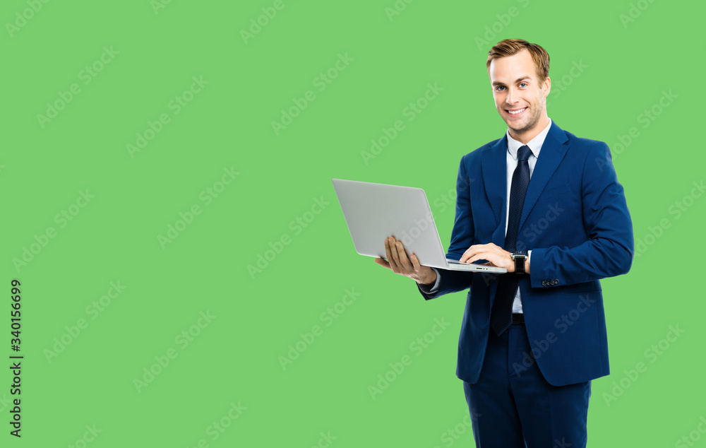 Happy smiling businessman in blue confident suit, working with laptop, isolated over green color background. Handsome young man at studio concept picture. Copy space for text. Happy smiling businessman in blue confident suit, working with laptop, isolated over green color background. Handsome young man at studio concept picture. Copy space for text.