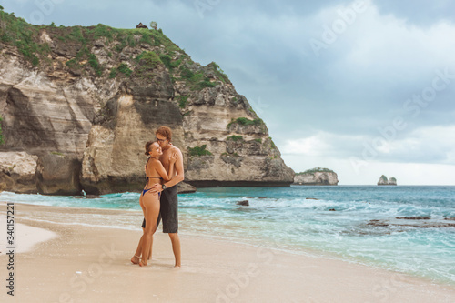 A girl and a Man walk along Diamond beach on the island of Nusa Penida.