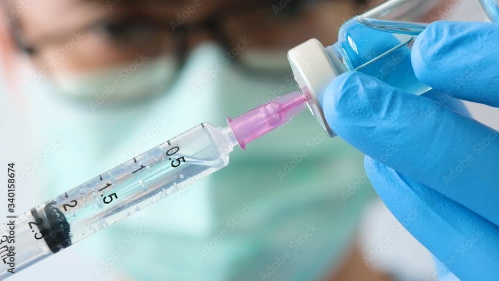 doctor's hand holds a syringe and a blue vaccine bottle at the hospital. Health and medical concepts doctor's hand holds a syringe and a blue vaccine bottle at the hospital. Health and medical concepts