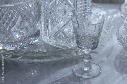 A collection vintage cut glass / crystalware. Pictured is a glass with a tray and decanters in the background photo