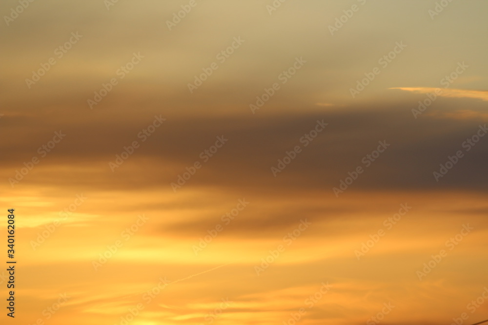 Sun below the horizon and clouds in the fiery dramatic orange sky at sunset or dawn backlit by the sun. Place for text and design.