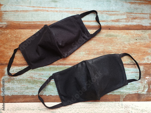 two black color Cloth mask made from cotton fabric on vintage wooden background.diy or handmade concept face mask for protect corona virus or covid-19 and air pollution.top view and flat lay