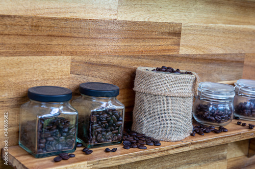 Coffee beans in a crystal jar on a brown wooden backgroundand photo