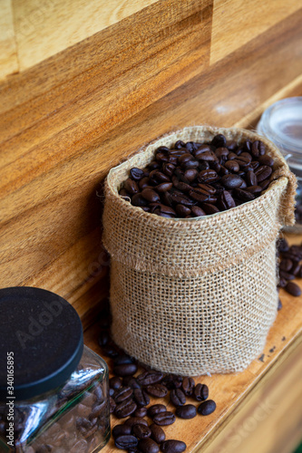 Coffee beans in a crystal jar on a brown wooden backgroundand photo