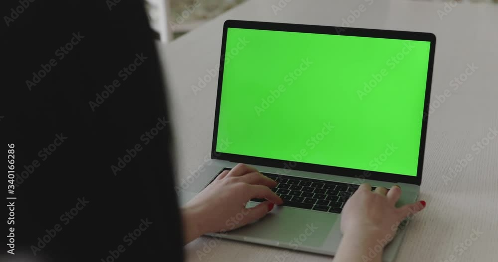 Background of female person working with laptop with green screen on table Background of female person working with laptop with green screen on table