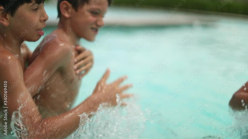 Two young brothers competing each other at swimming pool. Kids playing ...