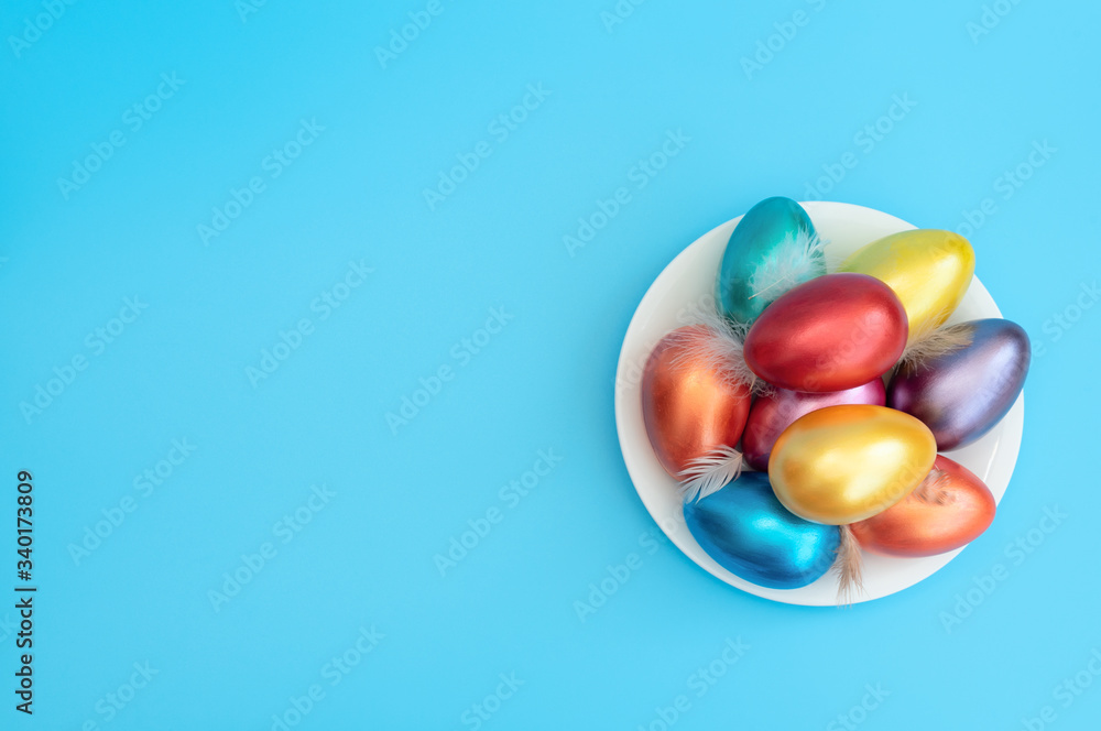 Decorated Easter eggs with small feathers lie on the plate on blue background. Happy Easter holiday concept. Greeting, invitation card. Flat lay style with copy space. Decorated Easter eggs with small feathers lie on the plate on blue background. Happy Easter holiday concept. Greeting, invitation card. Flat lay style with copy space.