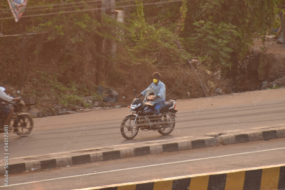 A person going on bike for purchasing essentials during lock down in india, due to covid or corona. A person going on bike for purchasing essentials during lock down in india, due to covid or corona.