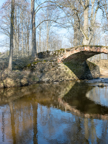 The Masonry bridge bridge over the river of Cuja, a sunny day in early spring with clear blue skies, the banks of a small river