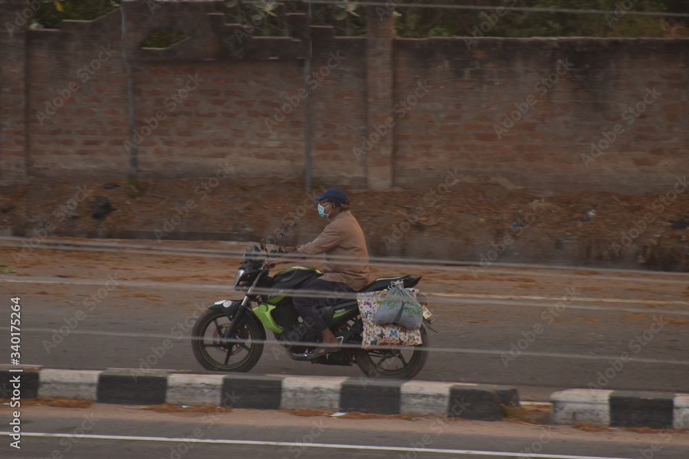 A person going on bike for purchasing essentials during lock down in india, due to covid or corona. A person going on bike for purchasing essentials during lock down in india, due to covid or corona.