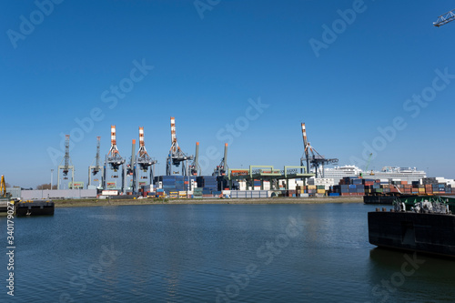 Huge cranes and ships anchored at harbor. International commercial port, city of Rotterdam background. Logistics business