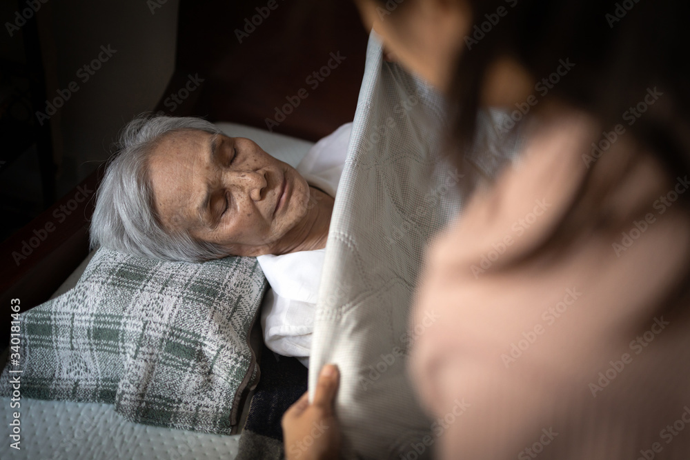 Asian senior woman is sleeping on a bed in bedroom,female caregiver