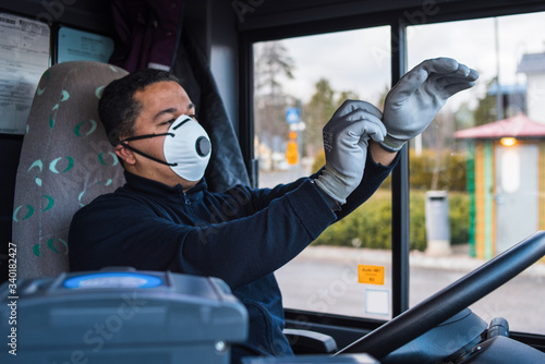 young hispanic bus driver wears a face mask to protect himself from the coronavirus epidemic