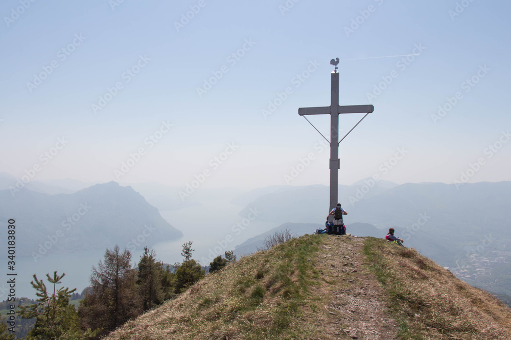 Colombina mountain peak with tourists, cross and blue sky on background.