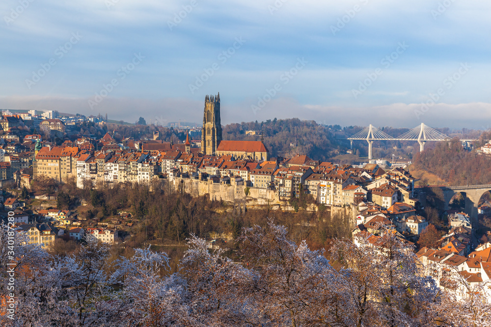 Stunning aerial panorama view of Fribourg (Freiburg) old town skyline with Fribourg Cathedral in middle from Bourguillon Gate on sunny winter day with blue sky cloud, Switzerland