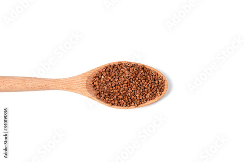 Dry buckwheat on wooden spoon isolated on white background.