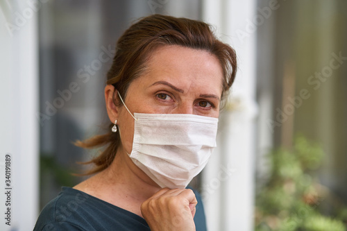 Women puts on respiratory mask. Doctor woman puts on face mask and looks at camera. Cold, flu, virus, tonsillitis, acute respiratory disease, quarantine, epidemic concept. Close-up