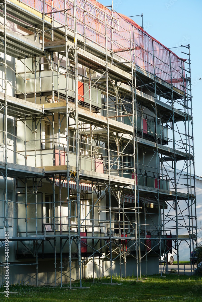 apartment house with scaffolding and protective net, for reconstruction and installation of insulation closeup, in detail