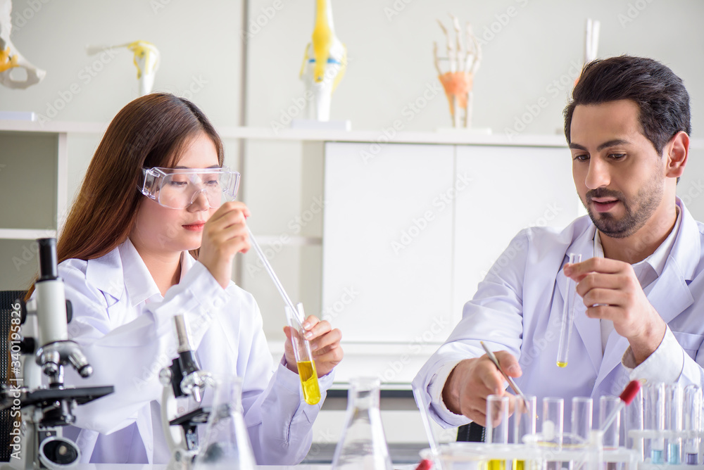 Attractive happiness scientist lab technician assistant analyzing sample in test tube at laboratory. Medical, pharmaceutical and scientific research and development concept. Attractive happiness scientist lab technician assistant analyzing sample in test tube at laboratory. Medical, pharmaceutical and scientific research and development concept.