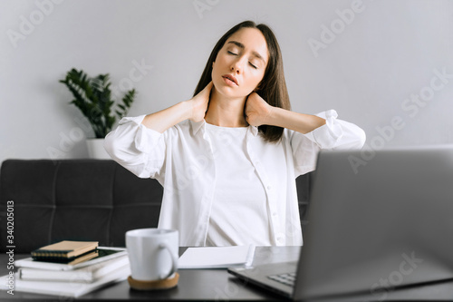 Tired young business woman or student using laptop at the home office and have a neck pain.