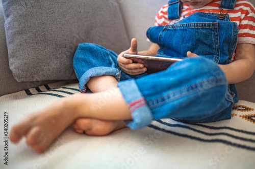 Child and electronic devices concept. Little boy sitting at home and playing with mobile phone. Kids and mobile devices. Children and technology. Fun time with mobile phone for kids. 