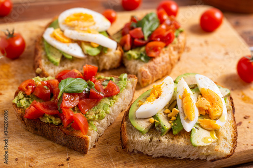 Mixed avocado toast with boiled eggs and tomatoes. Ideas for fast and nutritious dish. Summer food.