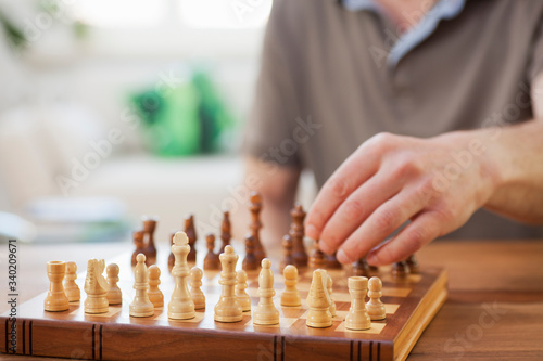 Man playing chess with a wooden chessboard in a bright living room