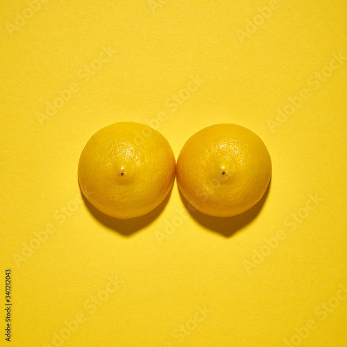 Two yellow lemons on a bright yellow background, imitation of a beautiful female breast. photo
