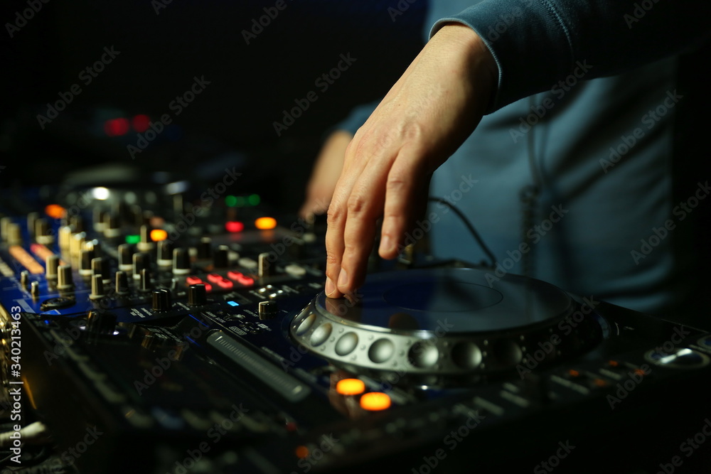hands of dj are mixing tracks at party in night club. disc jockey playing music on the modern turntable close up. hands of dj are mixing tracks at party in night club. disc jockey playing music on the modern turntable close up.