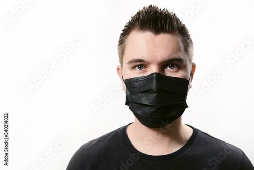 Closeup man in disposable medical mask isolated on a white background. Covid-19 coronavirus epidemic. Quarantine and self-isolation mode to save the population. © ANR Production