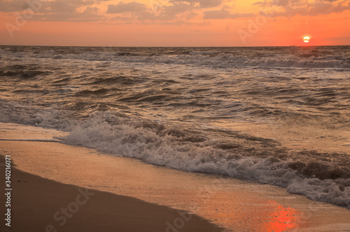 Fototapeta Naklejka Na Ścianę i Meble -  Natural background for text and sand and sea waves. Footprints in the sand from the legs go into the distance. Summer, sea, sunrise.