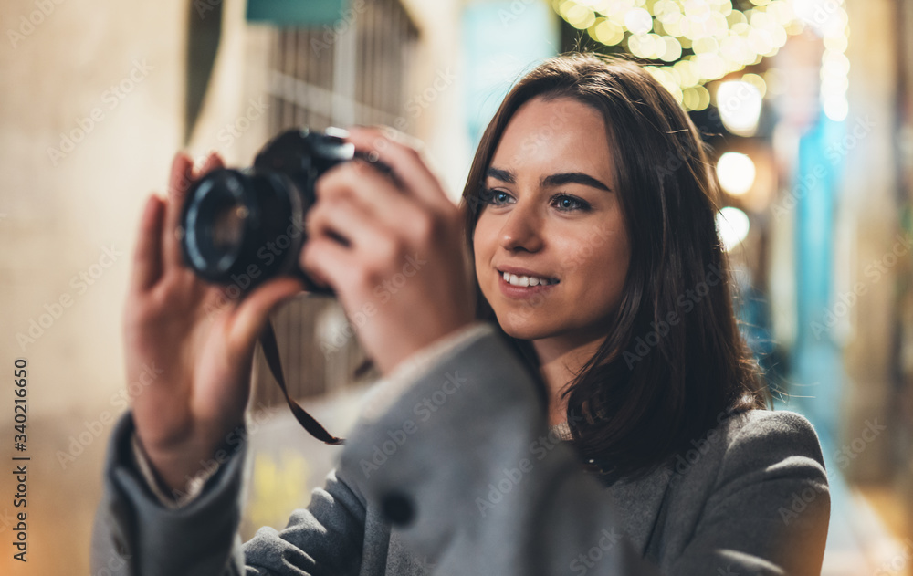 Photographer girl with retro camera take photo on background bokeh light in night city, Blogger photo hobby. Outdoor portrait of young smile woman hold in hands video technology.