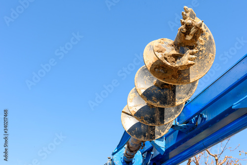 Tracer tractor with auger for soil drilling for piles installation