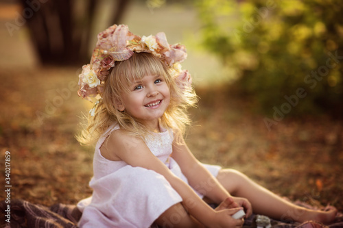 Beautiful blond girl with flowers sitting in the park