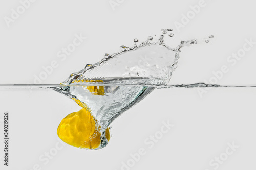 ripe yellow lemon hoop splashing into transparent water