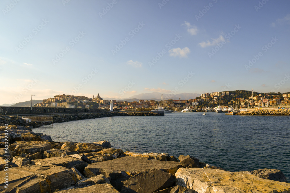 Scenic view of the bay of Porto Maurizio from a rocky breakwater with the harbor and the fishing village in the background in a sunny day, Imperia, Liguria, Italy