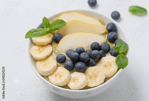 Healthy Breakfast smoothie in a bowl with banana, pear, kiwi, blueberry, lime and mint. The concept of healthy eating.