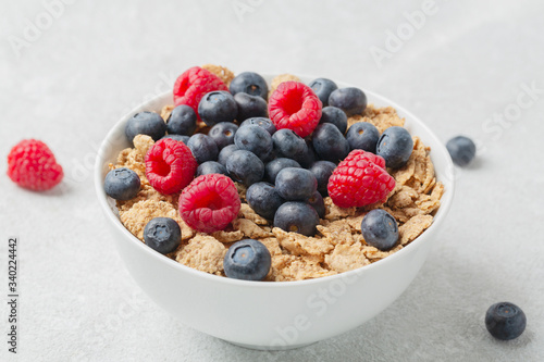 Multigrain wholewheat healthy cereals with fresh berry for breakfast. Bowl flakes with fresh berries raspberries and blueberries. 