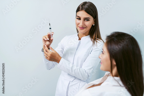 Beautician with syringe with filler for facial contouring or augmentation. Doctor doing beauty procedure for patient. Cosmetological clinic. Healthcare  cosmetology. Hyaluronic acid  scincare concept