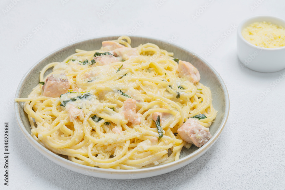 Spaghetti with salmon, cream cheese and spinach on plate. Italian cuisine. Spaghetti with salmon, cream cheese and spinach on plate. Italian cuisine.