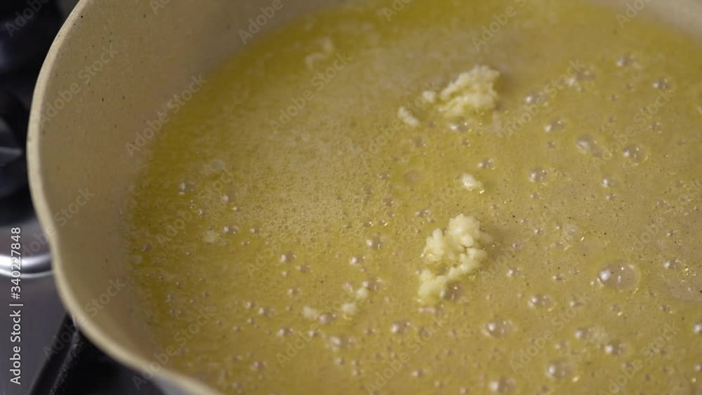 Putting garlic on melting butter in pan, close up shot. Garlic roasting and frying in the melted butter on the pan. Putting garlic on melting butter in pan, close up shot. Garlic roasting and frying in the melted butter on the pan.