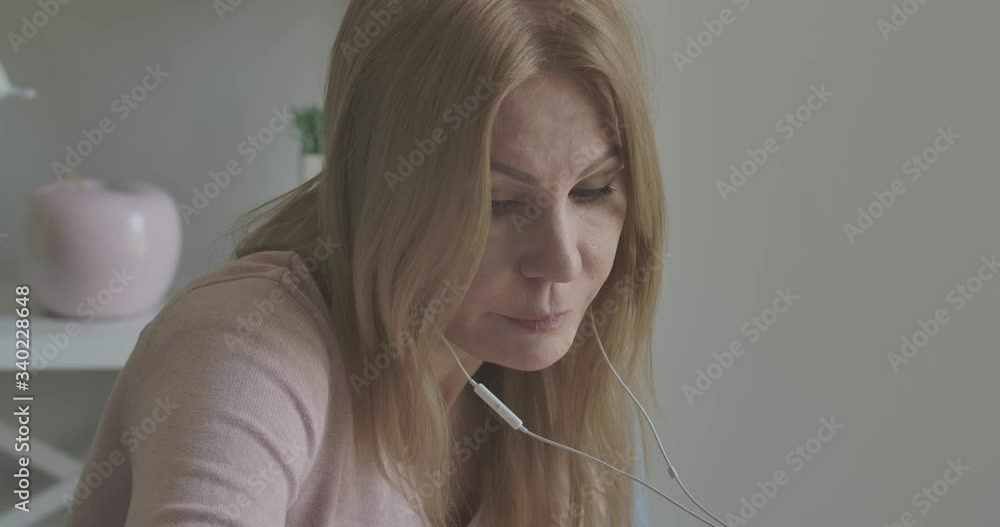 Portrait of blond Caucasian woman in headphones discussing project distantly on Covid-19 lockdown. Side view of confident serious lady talking and having video call at home. Cinema 4k ProRes HQ. Portrait of blond Caucasian woman in headphones discussing project distantly on Covid-19 lockdown. Side view of confident serious lady talking and having video call at home. Cinema 4k ProRes HQ.