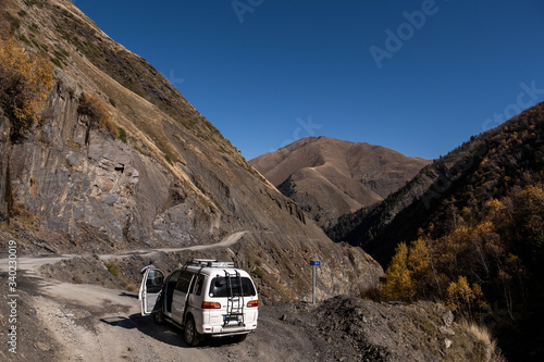A man repairs a car on the road to Omalo - Tusheti with mountains in the background